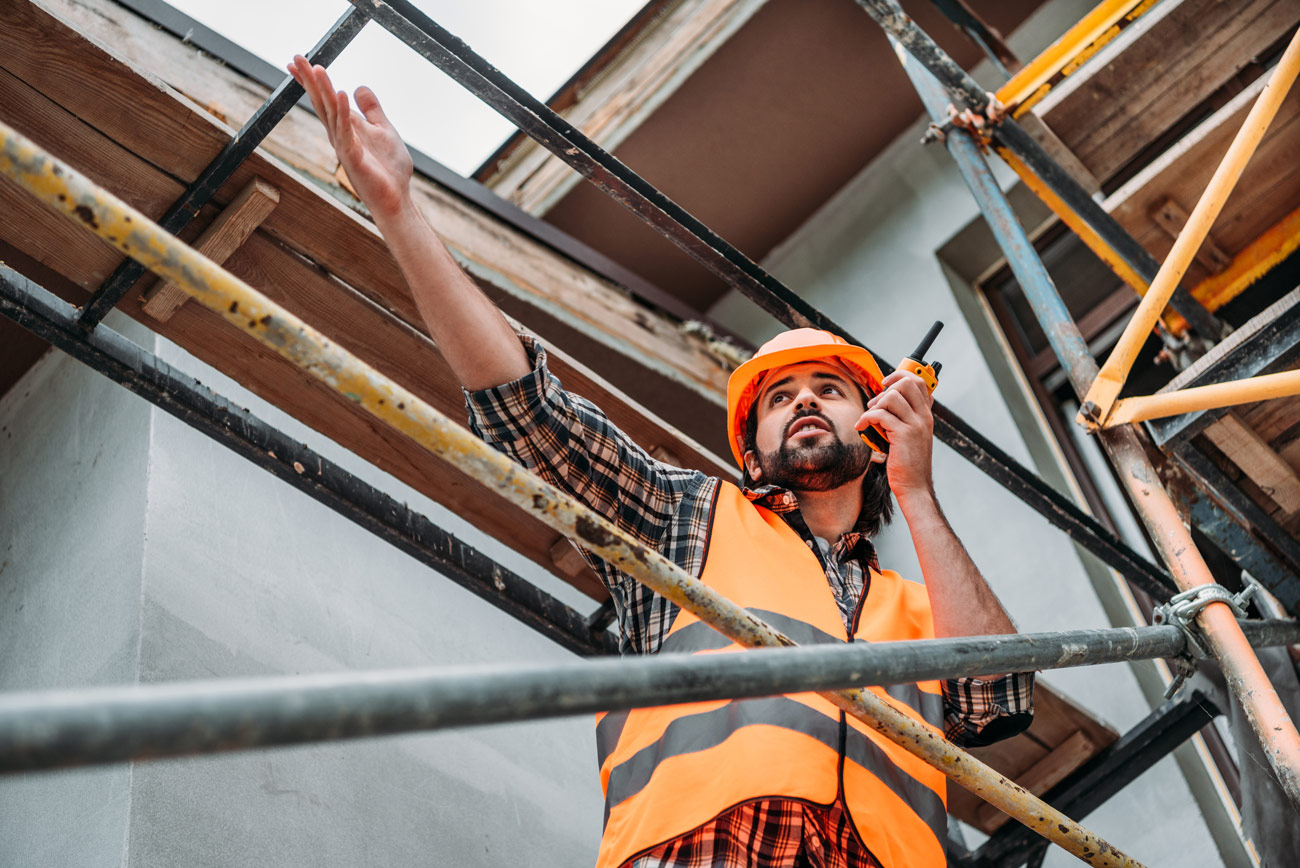 Construction worker pointing forward and talking into radio